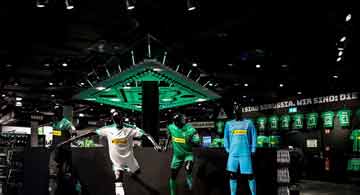 Modernes, zweistöckiges Haus mit großer Fensterfront, stilvoller Außenbeleuchtung und gepflegtem Garten bei Dämmerung.